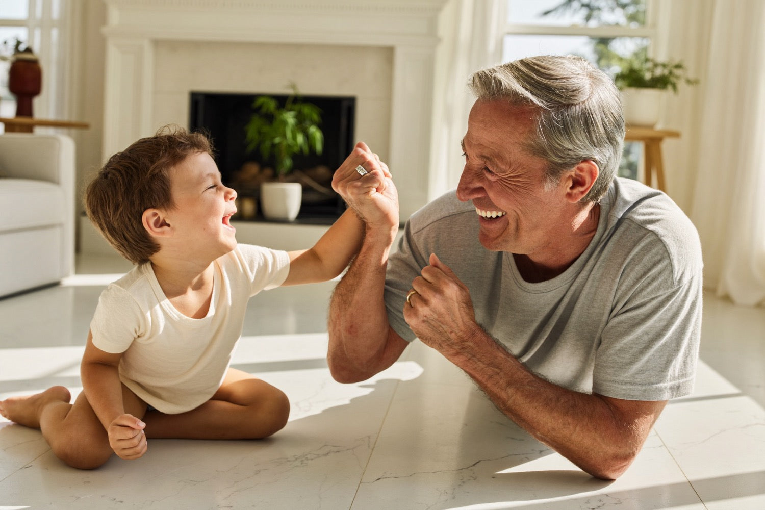 A grandparent down on the floor playing with a laughing grandchild
